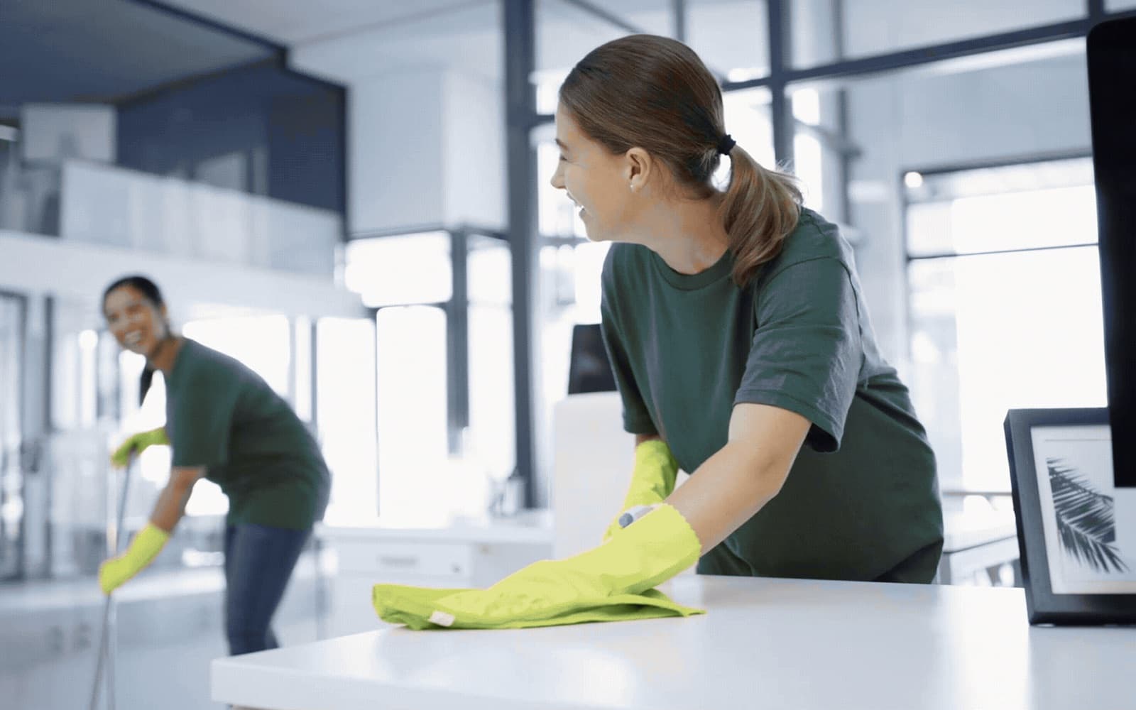 Dos personas limpiando superficies en una habitación iluminada